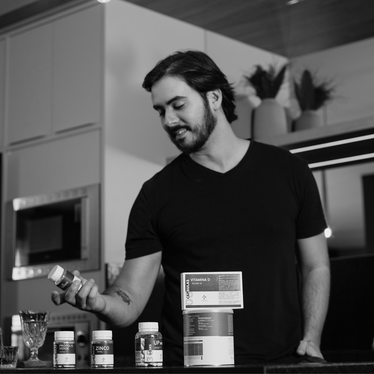 Man holding supplement bottles in kitchen